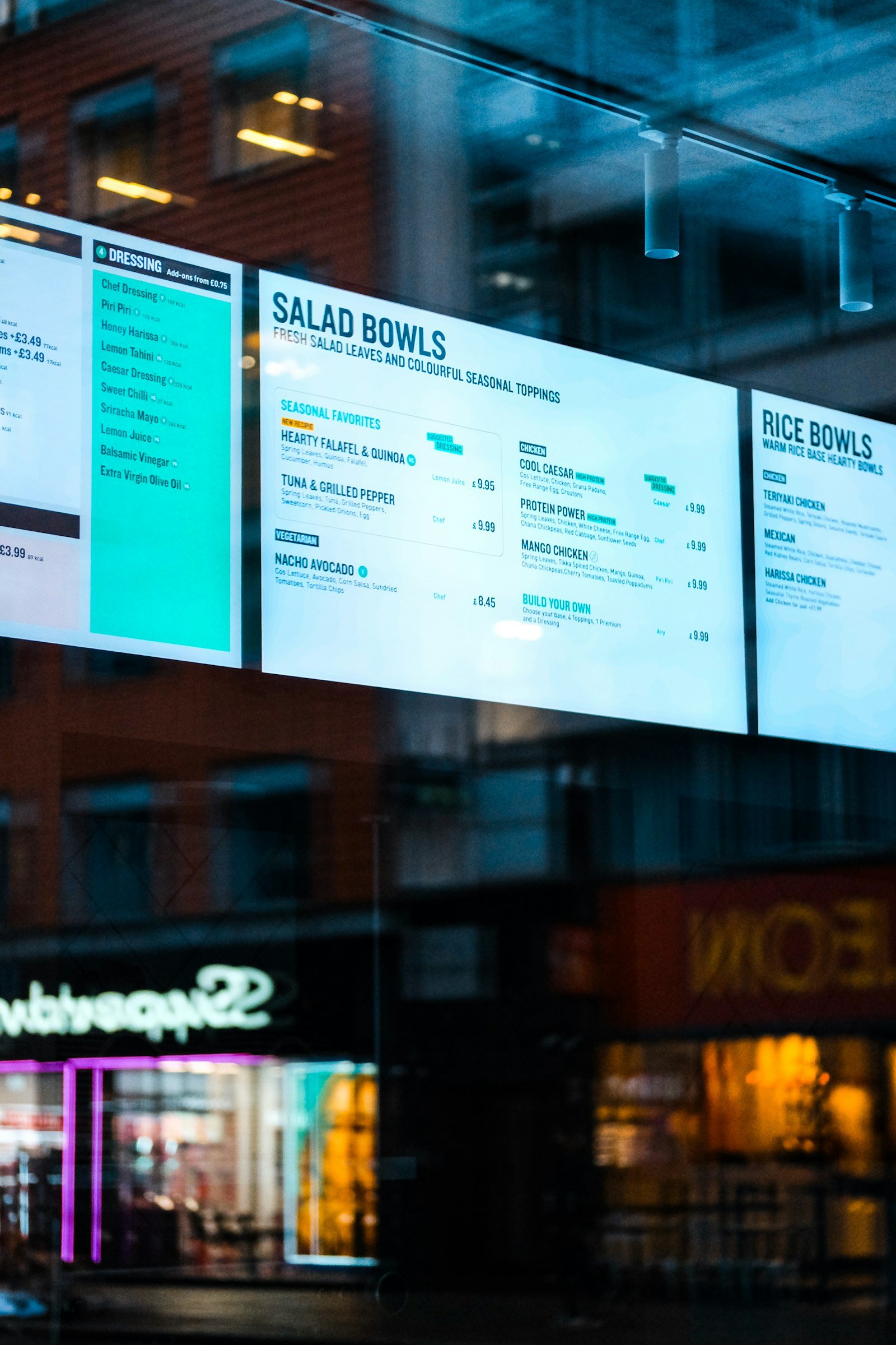 Tela digital exibindo cardápio em vitrine de loja à noite